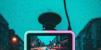 Dash Cams Under $100 That Record in 4K A dash cam on a windshield, capturing a glowing city street at dusk.